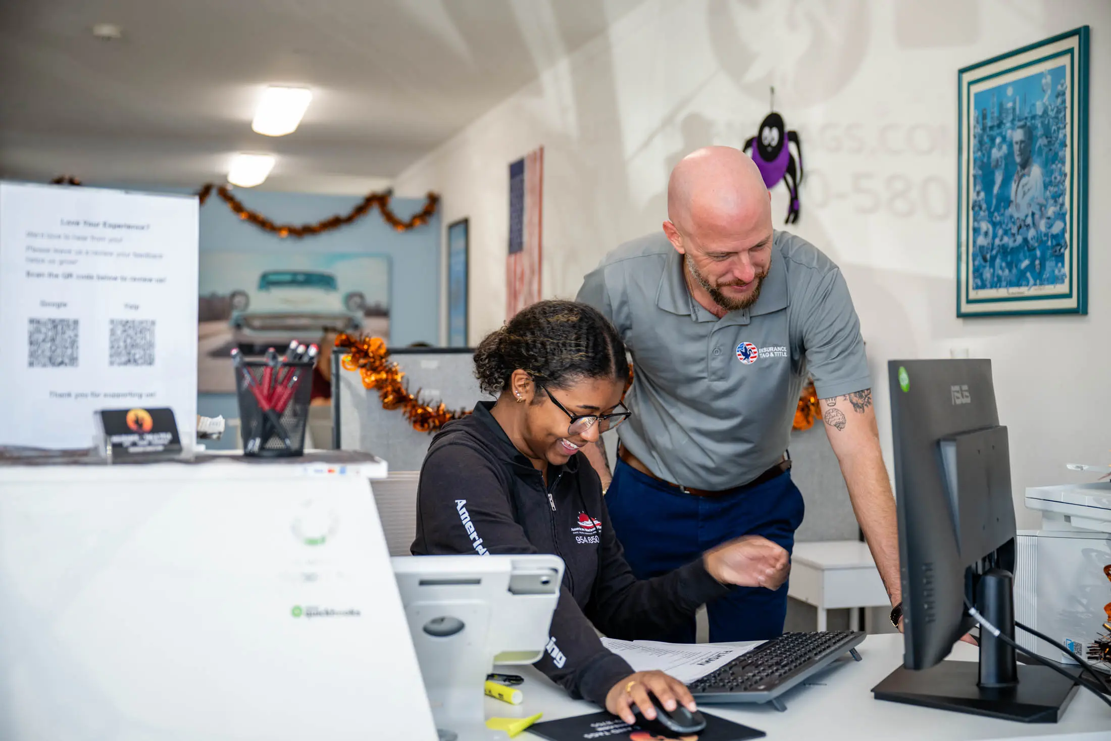 Two coworkers collaborating at a computer desk.